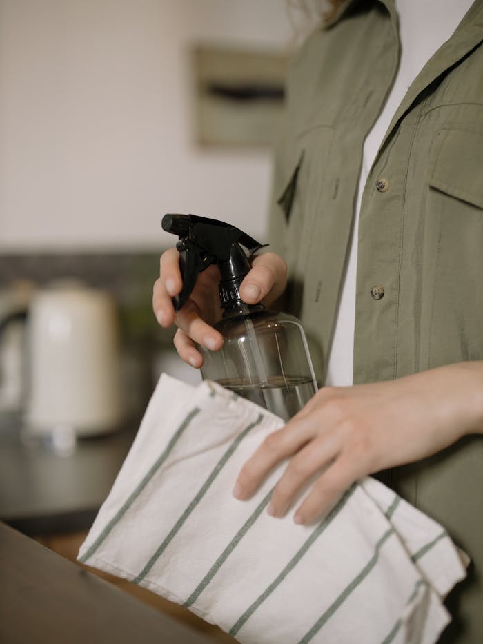 Close-up shot of a person cleaning with a spray bottle and cloth. Ideal for cleaning and home care themes.
